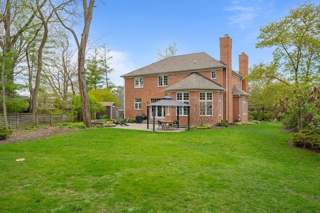 rear view of property with a gazebo, a patio area, a chimney, and brick siding