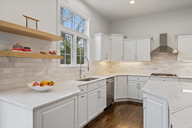 kitchen with wall chimney range hood, a sink, appliances with stainless steel finishes, white cabinetry, and recessed lighting