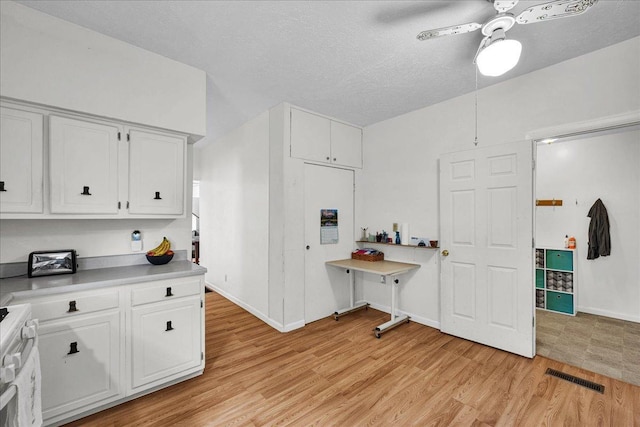 1216 N Oak St, Bloomington, IL 61701 - kitchen featuring white cabinets, light wood finished floors, stove, ceiling fan, and light countertops