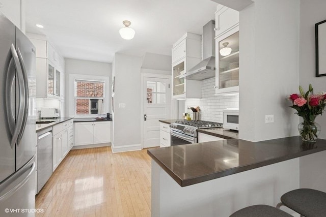 2206 Forestview Rd, Evanston, IL 60201 - kitchen with stainless steel appliances, wall chimney exhaust hood, tasteful backsplash, white cabinets, and a peninsula