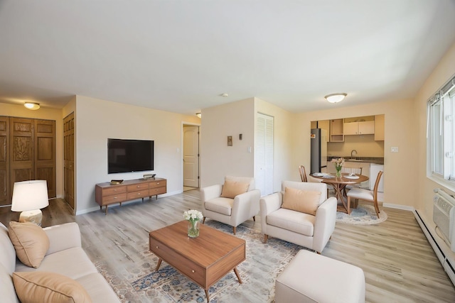 living room featuring a baseboard radiator, light wood-type flooring, and baseboards