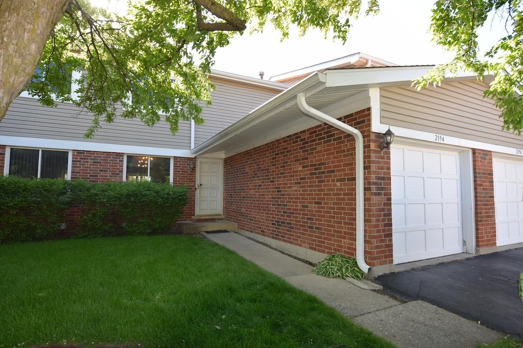2194 N Queensburg Cir, Palatine, IL 60074 - view of side of home featuring an attached garage, brick siding, and a yard
