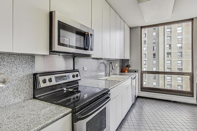 kitchen featuring stainless steel appliances, a sink, white cabinets, and decorative backsplash