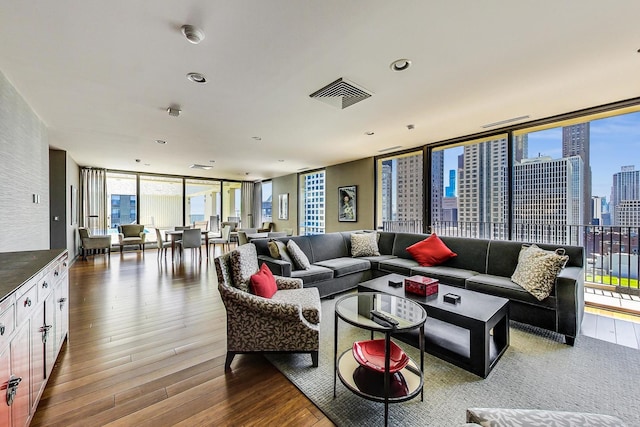 living area with expansive windows, wood finished floors, and a skyline view