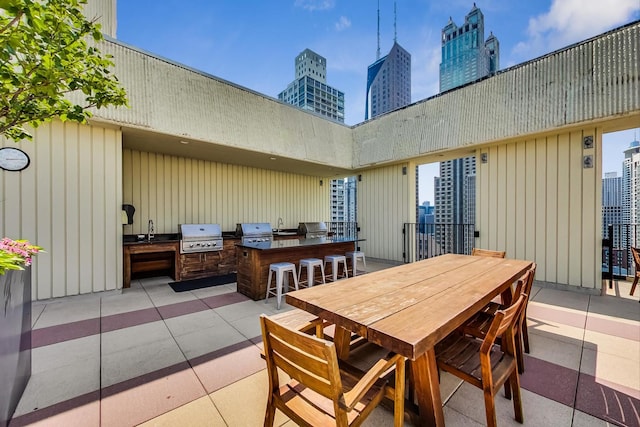 view of patio with exterior kitchen, grilling area, outdoor dining space, and a view of city
