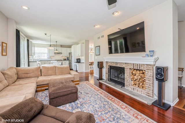 7181 Dada Dr, Gurnee, IL 60031 - living room featuring dark wood-type flooring, baseboards, a brick fireplace, recessed lighting, and ceiling fan