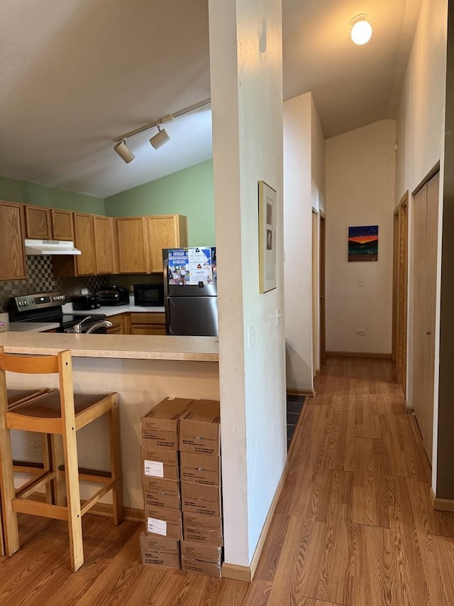 1646 Mcclure Rd Unit 1646, Aurora, IL 60505 - kitchen with freestanding refrigerator, under cabinet range hood, black microwave, stainless steel electric range oven, and vaulted ceiling