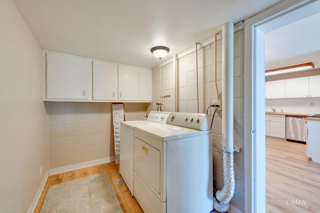 231 Barcliffe Ln Unit 231, Schaumburg, IL 60194 - clothes washing area with washer and dryer, cabinet space, light wood-style flooring, concrete block wall, and baseboards