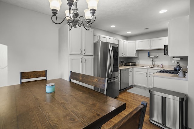 8 Harrison Ct, Bloomington, IL 61704 - kitchen with appliances with stainless steel finishes, a chandelier, a sink, light countertops, and dark wood-type flooring