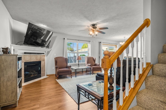 8 Harrison Ct, Bloomington, IL 61704 - living area with wood finished floors, a tile fireplace, a ceiling fan, a textured ceiling, and stairway