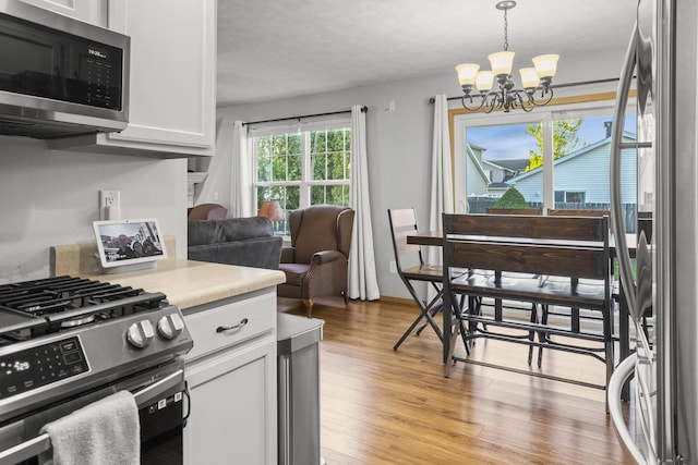 8 Harrison Ct, Bloomington, IL 61704 - kitchen with appliances with stainless steel finishes, a chandelier, light wood finished floors, white cabinetry, and light countertops