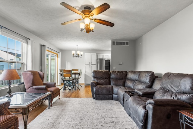 8 Harrison Ct, Bloomington, IL 61704 - living room featuring a chandelier, light wood finished floors, a ceiling fan, and a textured ceiling