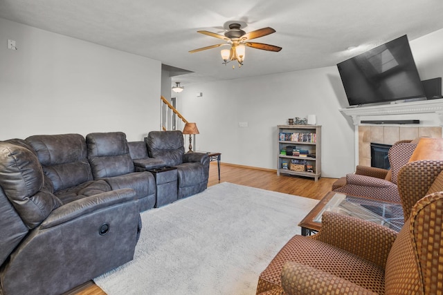 8 Harrison Ct, Bloomington, IL 61704 - living room featuring wood finished floors, ceiling fan, a tiled fireplace, and stairs