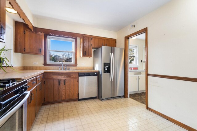 12217 S 68th Ct, Palos Heights, IL 60463 - kitchen featuring appliances with stainless steel finishes, light floors, tile counters, a sink, and brown cabinets