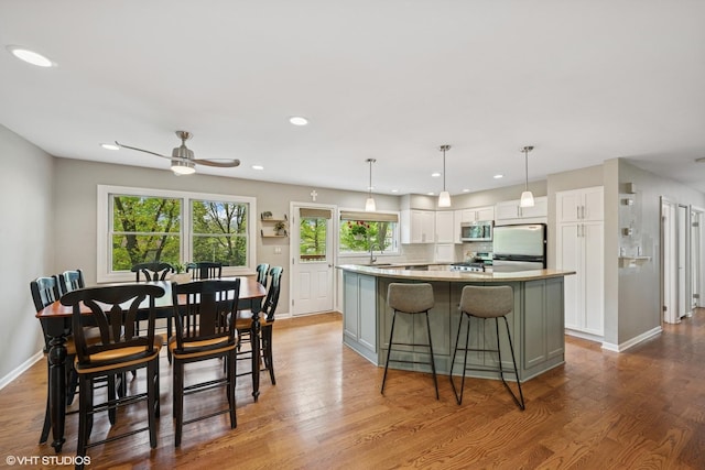 153 E Timberlane Dr, Palatine, IL 60067 - kitchen with stainless steel microwave, freestanding refrigerator, a kitchen island, a sink, and white cabinetry