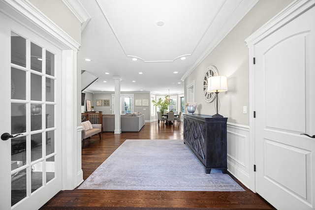 corridor featuring recessed lighting, ornamental molding, wood finished floors, decorative columns, and a wainscoted wall