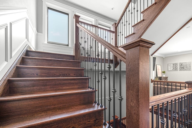 staircase featuring ornamental molding and a decorative wall