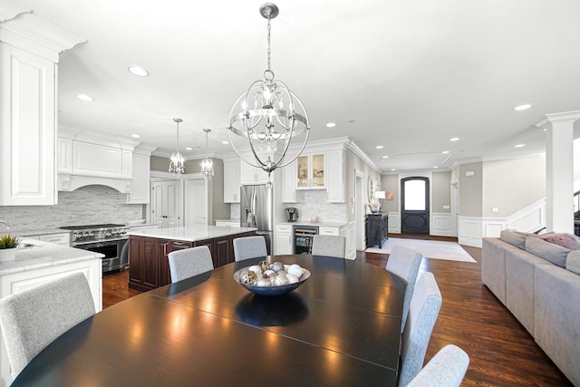 dining room featuring recessed lighting, decorative columns, beverage cooler, crown molding, and dark wood-style flooring