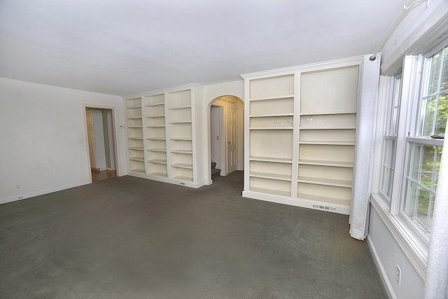 122 W Allen St, Ottawa, IL 61350 - empty room with arched walkways, dark colored carpet, built in shelves, and baseboards