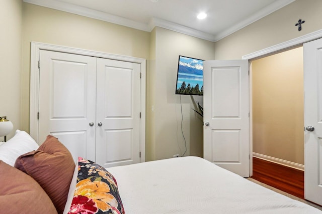 bedroom with crown molding, wood finished floors, a closet, recessed lighting, and baseboards