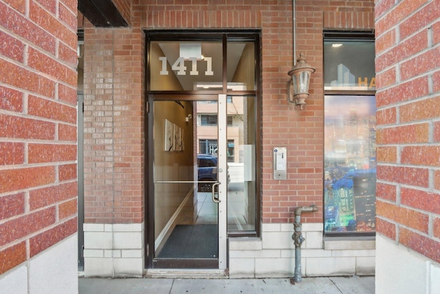 view of exterior entry featuring brick siding