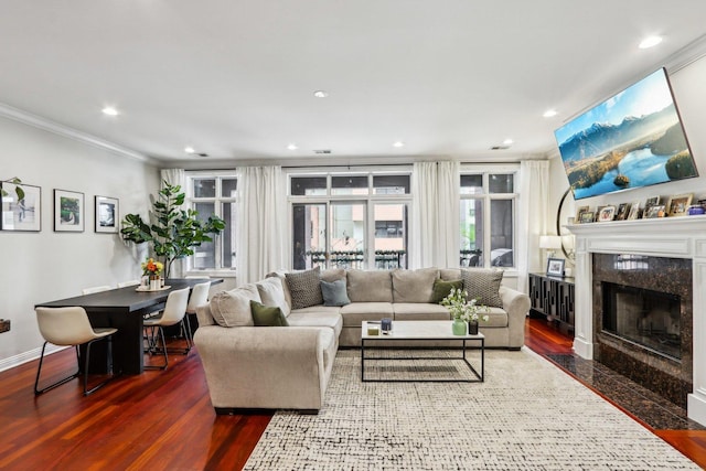 living room with crown molding, wood finished floors, a high end fireplace, recessed lighting, and baseboards