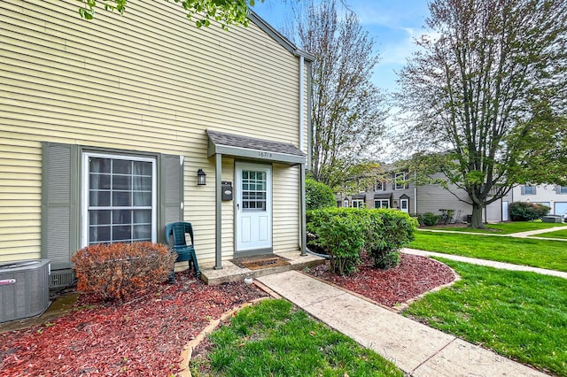 doorway to property with a lawn and central air condition unit