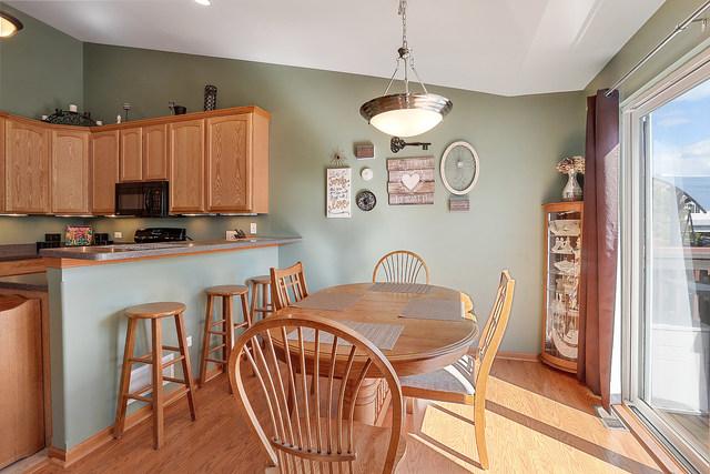 dining area featuring light wood-type flooring, vaulted ceiling, and baseboards