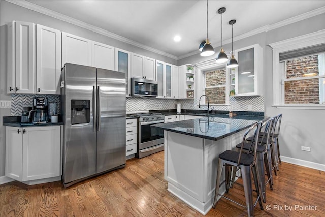 2447 W Walton St Unit 1, Chicago, IL 60622 - kitchen with appliances with stainless steel finishes, a sink, a kitchen breakfast bar, glass insert cabinets, and pendant lighting