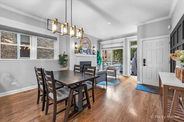 2447 W Walton St Unit 1, Chicago, IL 60622 - dining space featuring ornamental molding, baseboards, wood finished floors, a tiled fireplace, and a chandelier