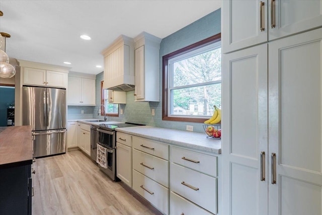 2201 Hedgewood Dr, Bloomington, IL 61704 - kitchen with stainless steel appliances, custom exhaust hood, light countertops, light wood-style floors, and tasteful backsplash