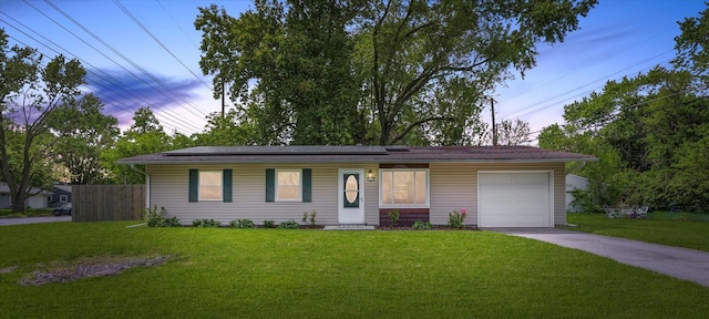 single story home with a garage, concrete driveway, and solar panels