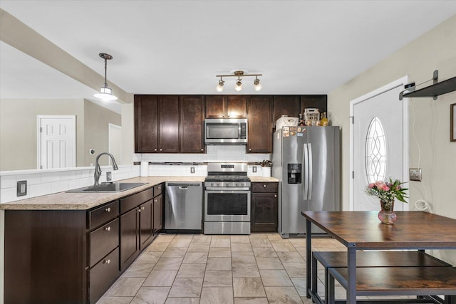kitchen featuring appliances with stainless steel finishes, a sink, dark brown cabinets, and tasteful backsplash