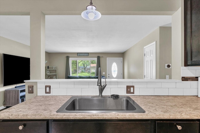 kitchen featuring a sink, light countertops, tasteful backsplash, and dark brown cabinets