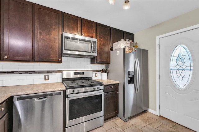 kitchen with stainless steel appliances, dark brown cabinets, tasteful backsplash, light countertops, and baseboards