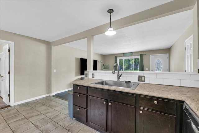 kitchen featuring a sink, dark brown cabinetry, light countertops, and baseboards