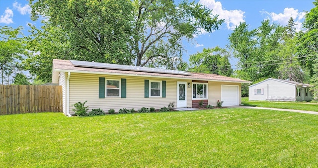 ranch-style house with a garage, roof mounted solar panels, and driveway