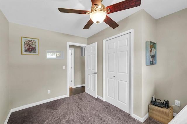 bedroom with dark carpet, baseboards, ceiling fan, and a closet