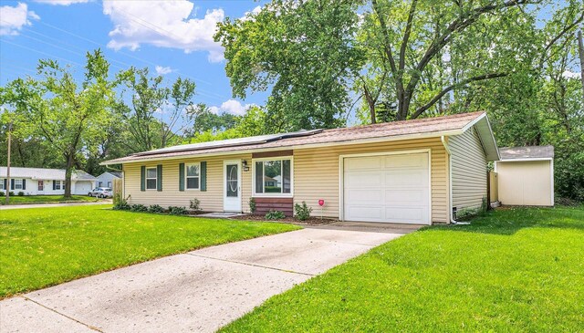 ranch-style home with a front lawn, an attached garage, concrete driveway, and solar panels