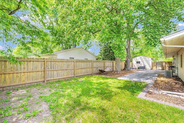 view of yard with an outbuilding, a patio area, a storage shed, and central AC unit