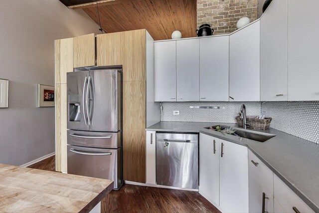 kitchen with stainless steel appliances, a sink, decorative backsplash, dark wood-style floors, and wooden ceiling