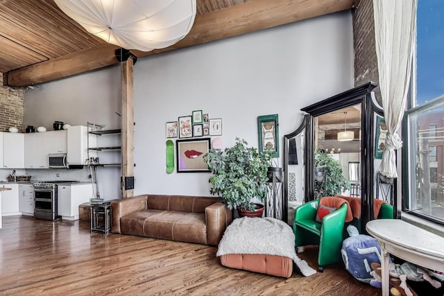 living area featuring wood finished floors, a high ceiling, beamed ceiling, and wooden ceiling