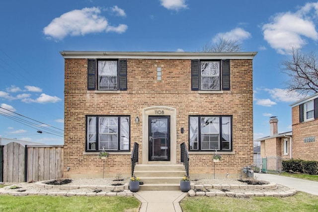 view of front of home with brick siding and fence