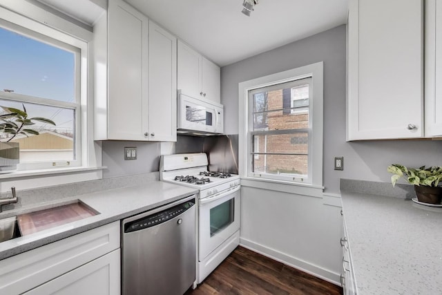 kitchen with white appliances, dark wood finished floors, baseboards, white cabinets, and light countertops