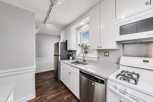 kitchen with appliances with stainless steel finishes, a sink, light countertops, track lighting, and white cabinets