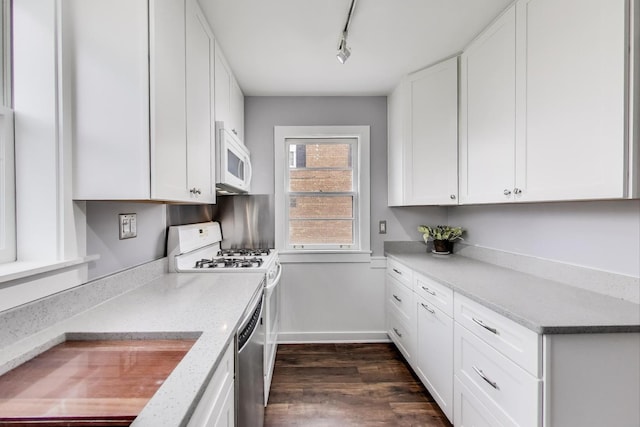 kitchen with white microwave, dark wood finished floors, rail lighting, baseboards, and white cabinets