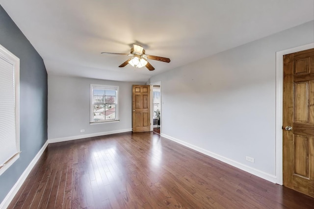 spare room with a ceiling fan, dark wood-type flooring, and baseboards