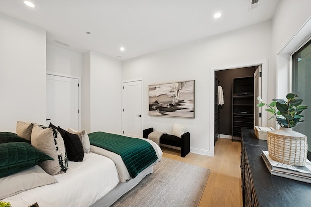 bedroom with light wood-style floors, recessed lighting, a closet, baseboards, and a walk in closet