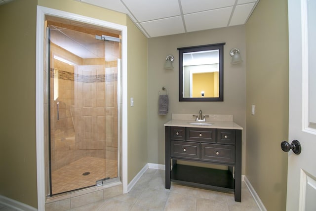 bathroom featuring a shower stall, tile patterned flooring, vanity, baseboards, and a paneled ceiling