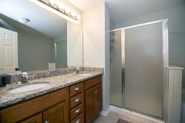bathroom with a stall shower, double vanity, and tile patterned floors